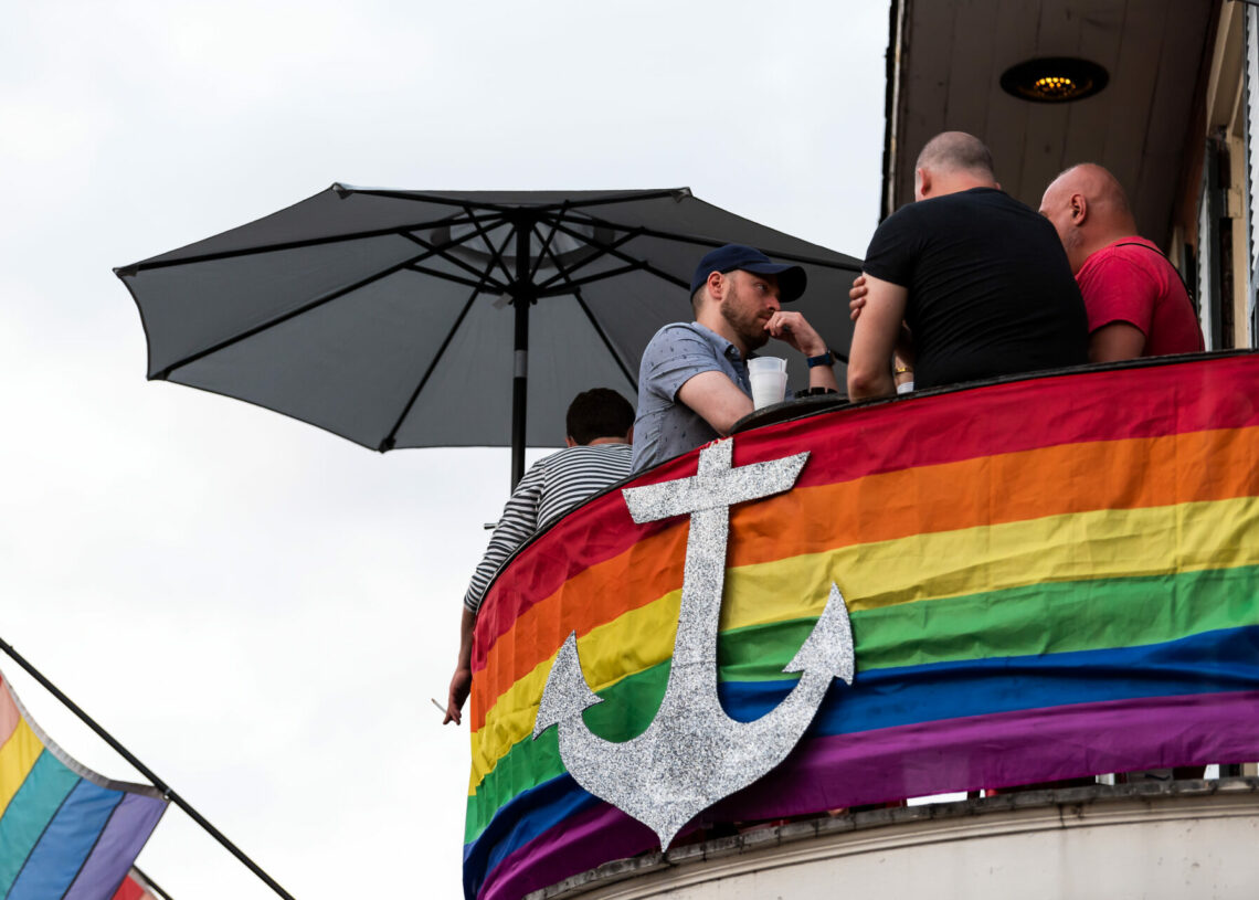 New Orleans, USA - April 22, 2018: Old town Bourbon street in Louisiana town, city, cast iron balcony building, party people standing by restaurant outdoor bar drinking beer during evening sunset night, architecture